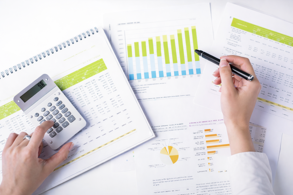 Person analyzing financial data using calculator and charts on documents